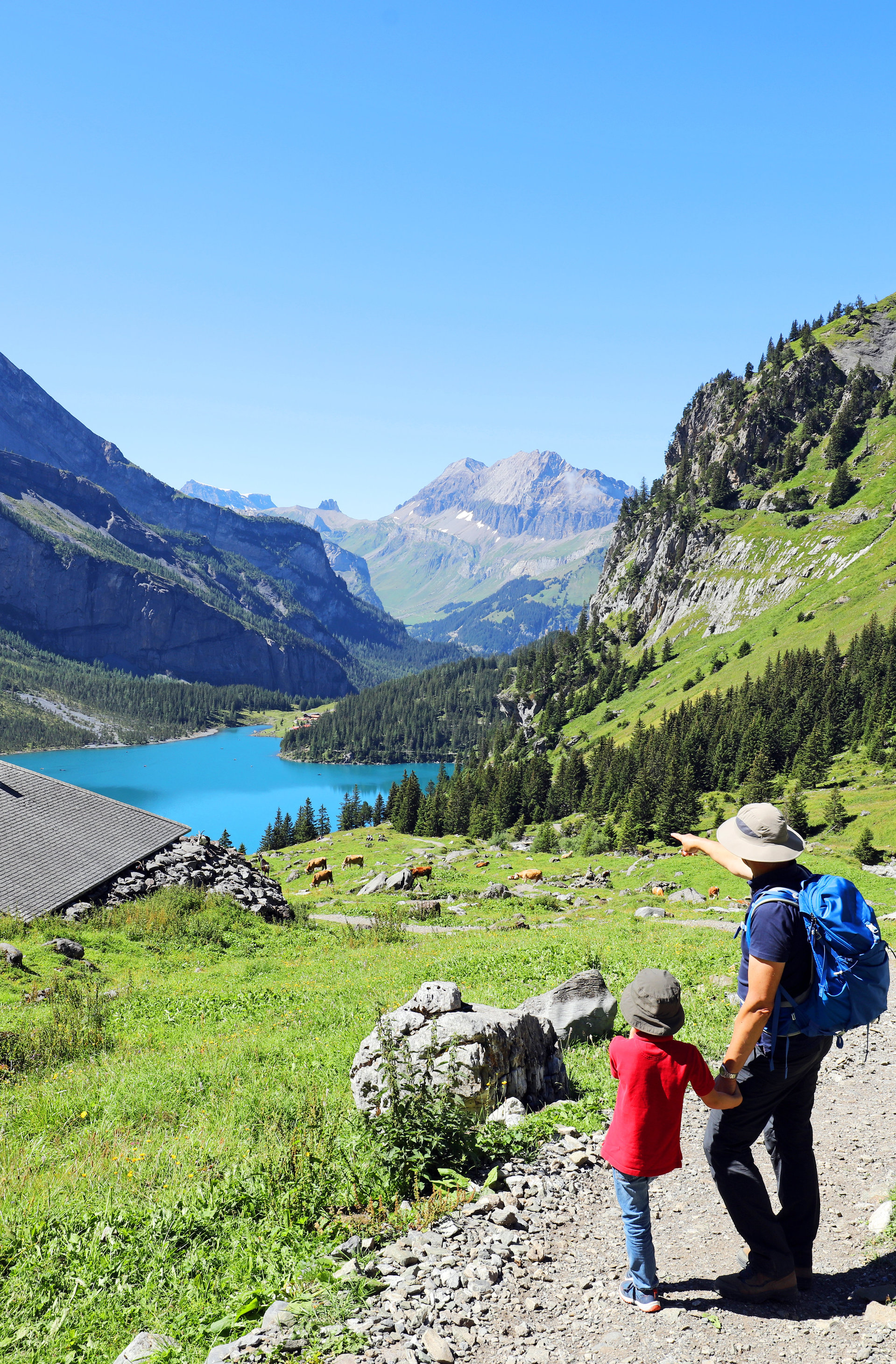 Wanderer mit Kind mit Ausblick auf Berge und einen See Wanderer mit Kind mit Ausblick auf Berge und einen See